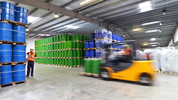 A forklift racing through a warehouse by a pedestrian