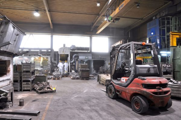 A dirty forklift parked in a machine shop