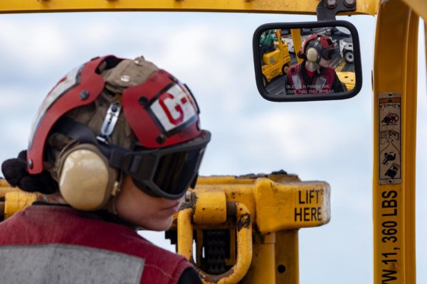 A military forklift operator looking behind them