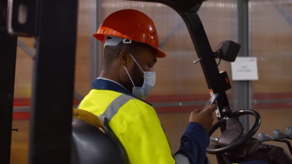 A forklift operator using a smart phone