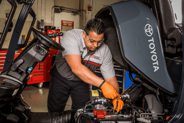 A forklift technician perform repairs on a forklift engine