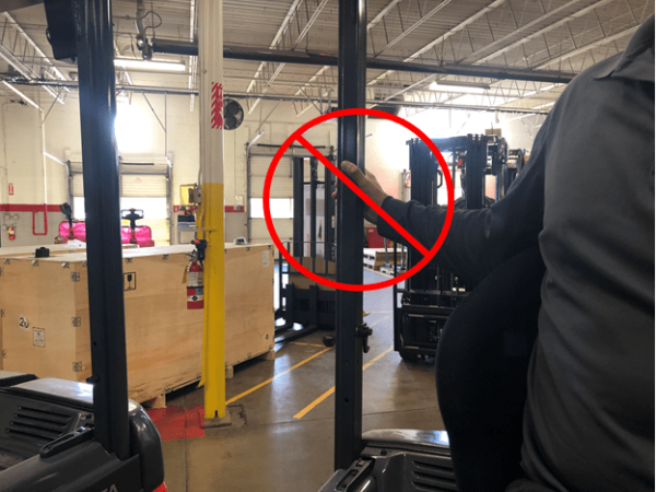 A forklift operator putting their hand on the outside of an overhead guard post