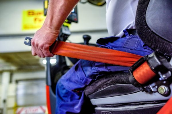 A forklift operator buckling their seat belt