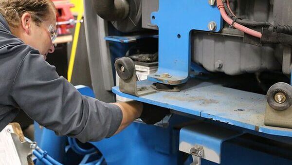 A technician performing an annual inspection on a boom lift