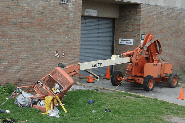 A boom lift that's collapsed beside a building