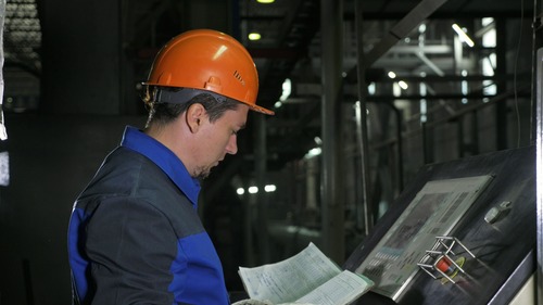 Worker in hard hat reviewing booklet