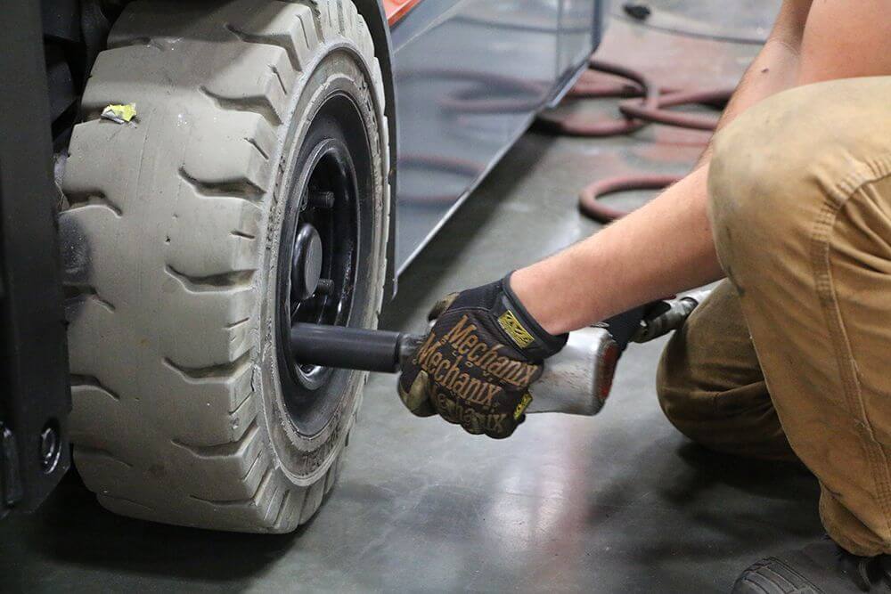 technician using impact gun on solid pneumatic forklift