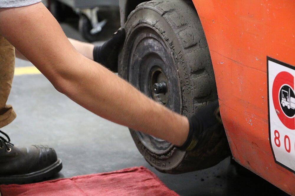 technician removes steer tires on forklift