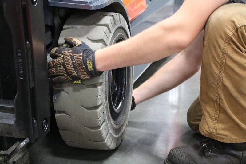 technician removes solid pneumatic from forklift