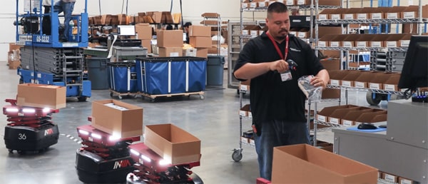 A cobot assisting a warehouse worker with a task