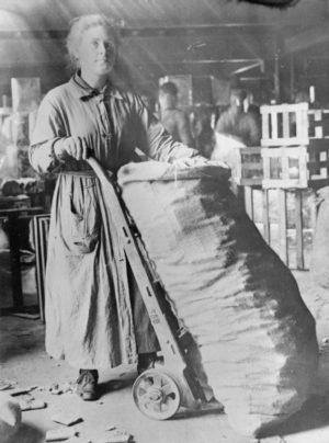 A woman moving a manual sack truck