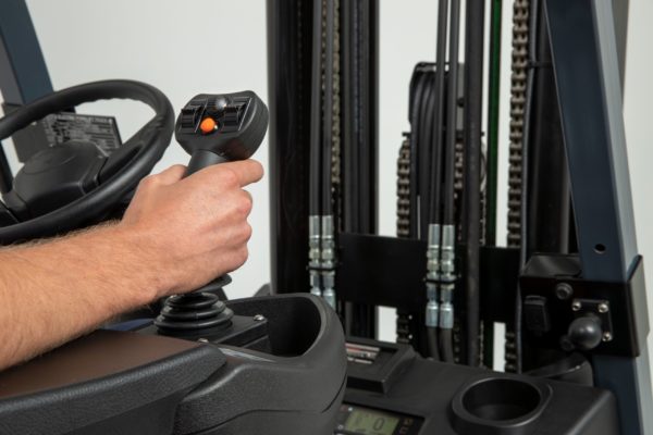 A forklift operator gripping the joystick controls of a Toyota forklift
