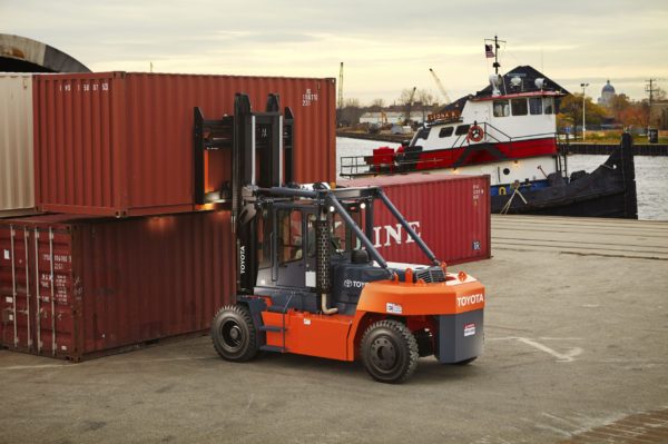 A Toyota high-capacity pneumatic forklift lifting a shipping container