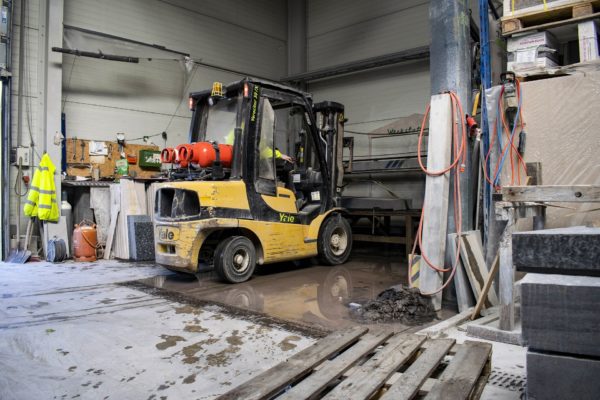 A yellow forklift in a wash bay