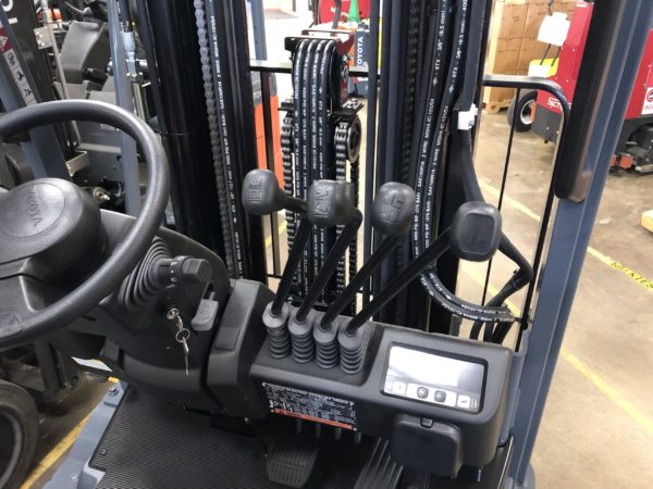Traditional lever-style hydraulic controls on an electric sit-down rider forklift