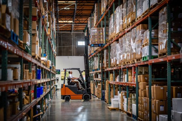 A Toyota forklift reaching up to retrieve a pallet from shelving