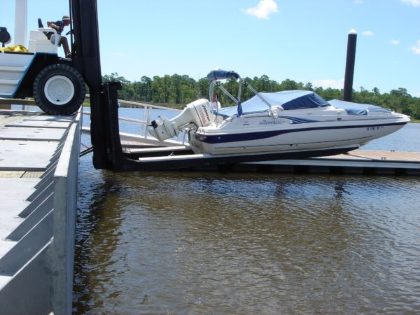 A marina forklift lowering a boat into the water