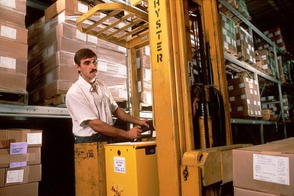 A worker operating a Hyster narrow aisle reach truck forklift
