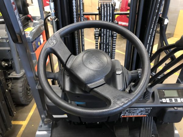 The steering wheel on an electric sit-down rider forklift