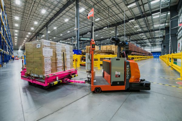 A Toyota AGV tow tractor pulling carts in a warehouse