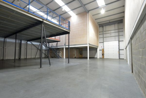 An empty warehouse space with a mezzanine visible