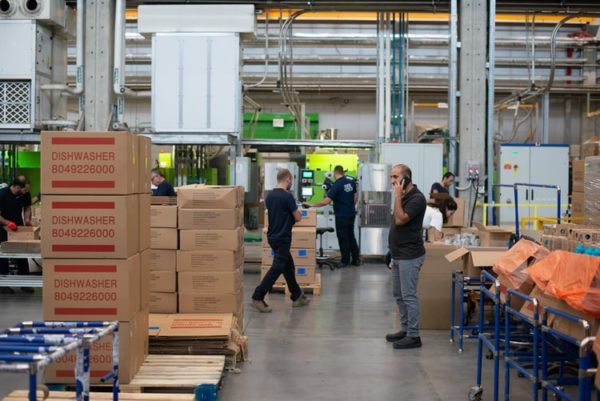 work-areas-safety Workers in a warehouse moving around as a supervisor talks on his phone
