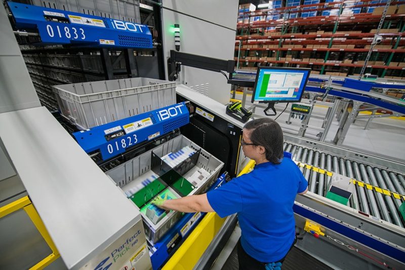 A worker using a Bastian pick-to-light system to package orders