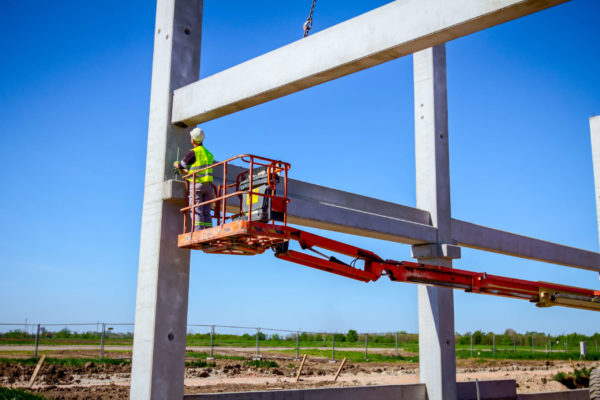 A worker on a boom lift platform working under a structural building beam