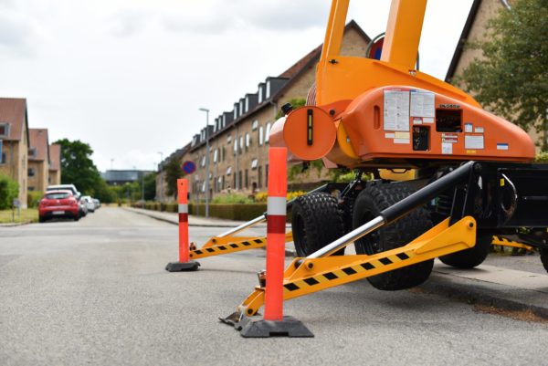 A boom lift with outrigger extended elevating on a sidewalk
