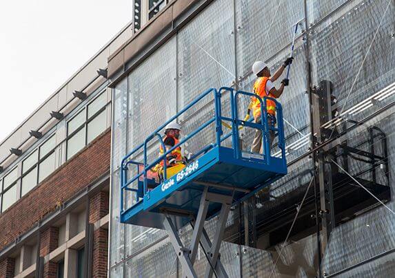 剪刀升降平台上的工人清洁建筑物的窗户