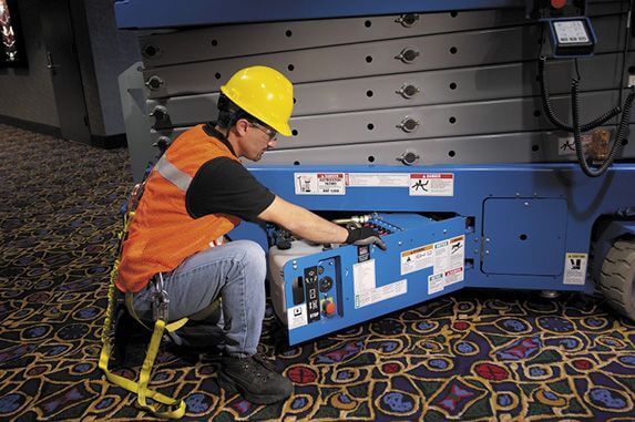 A scissor lift operator opening a compartment on a scissor lift