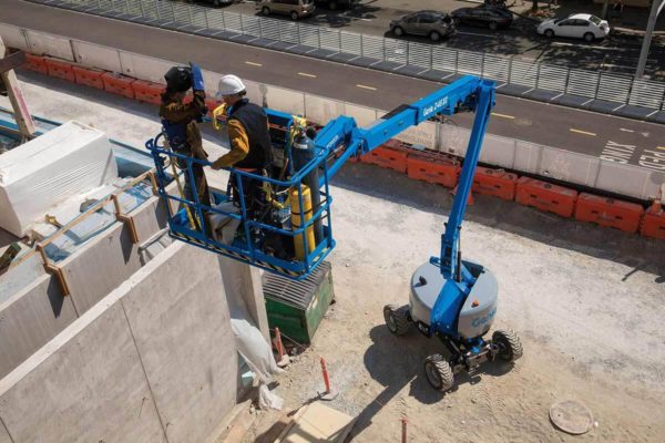 Two workers on an elevated boom lift platform on a construction site