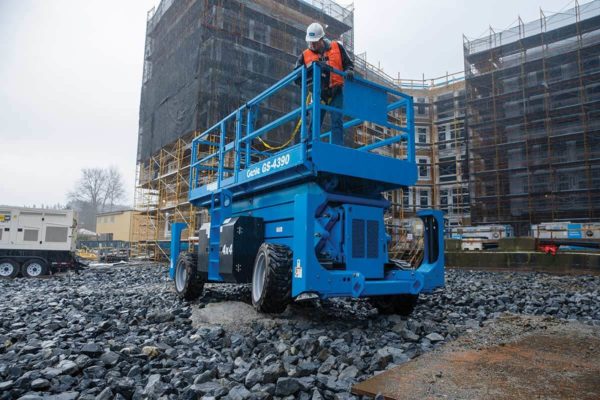 A scissor lift operator traveling over a large gravel pit