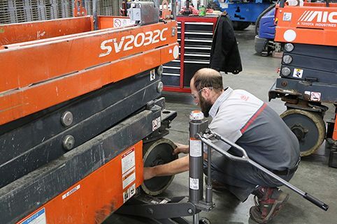 A technician replacing the steer wheel on a scissor lift