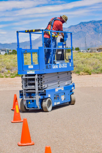 A scissor lift operator navigating a cone course during training