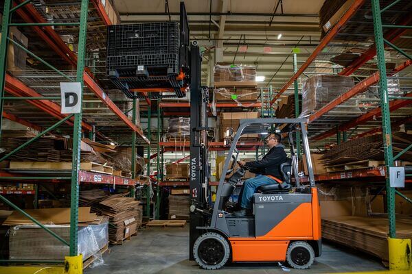 A forklift operator placing a pallet into racking
