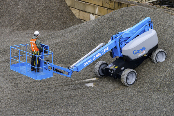A boom lift operator driving on a sloped pile of gravel