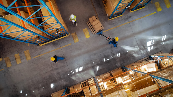 Warehouse workers meeting at the intersection of a pair of warehouse aisles