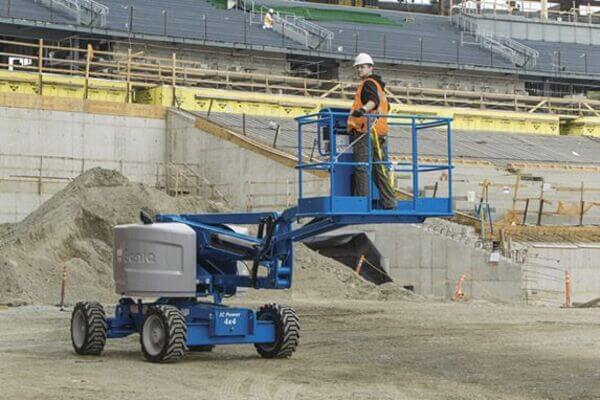 An operator driving a Genie articulating boom lift with the platform raised