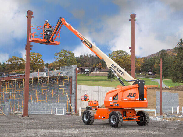 An operator in the basket of a JLG straight boom about to work on a vertical post