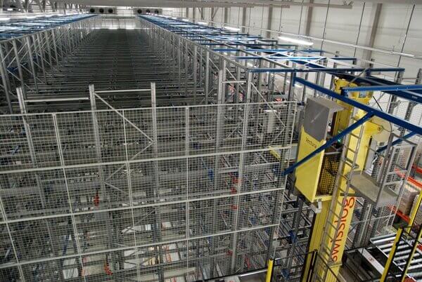 An ASRS crane shown at the top of warehouse racking