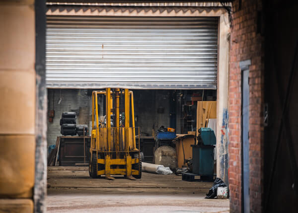 A forklift as seen through a half-closed garage door