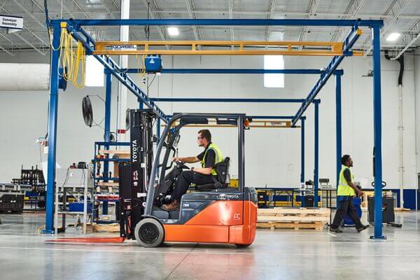 A Toyota sit-down forklift operator driving through a production zone