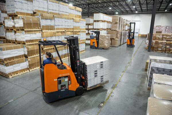 A stand-up forklift turning into an aisle in a warehouse