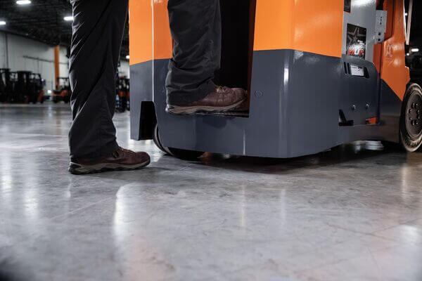 A stand-up forklift operator stepping into the operator compartment