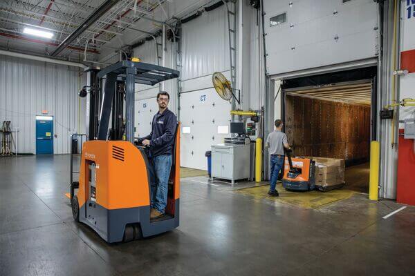 A stand-up forklift operator looking in reverse