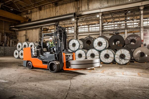 A high-capacity Toyota sit-down forklift carrying a roll of steel