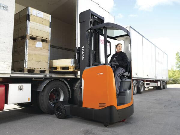 An operator of an outdoor reach truck model unloading a semi-trailer