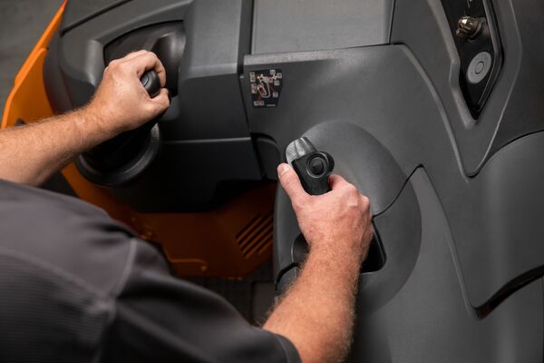 A reach truck operator with their hands on the steering wheel and joystick