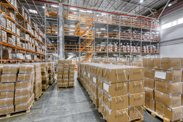 A warehouse with pallets on the ground and high pallet racking